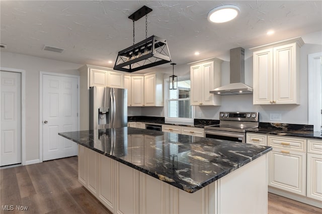 kitchen with wall chimney exhaust hood, a center island, decorative light fixtures, and appliances with stainless steel finishes