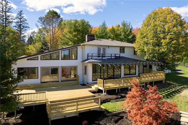 back of property with french doors, a sunroom, a lawn, and a wooden deck