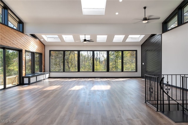 unfurnished sunroom with ceiling fan and vaulted ceiling with skylight