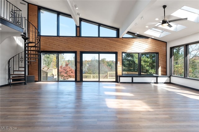 unfurnished living room with beamed ceiling, a skylight, high vaulted ceiling, and a wealth of natural light