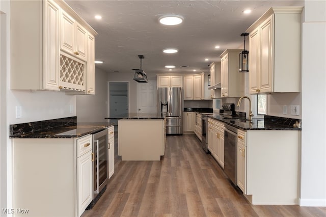 kitchen with a center island, beverage cooler, stainless steel appliances, wood-type flooring, and decorative light fixtures