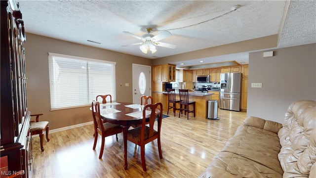 dining space featuring ceiling fan, a textured ceiling, and light hardwood / wood-style floors