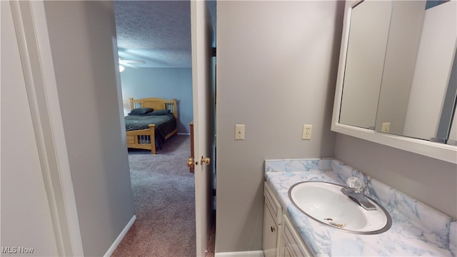 bathroom with vanity, ceiling fan, and a textured ceiling