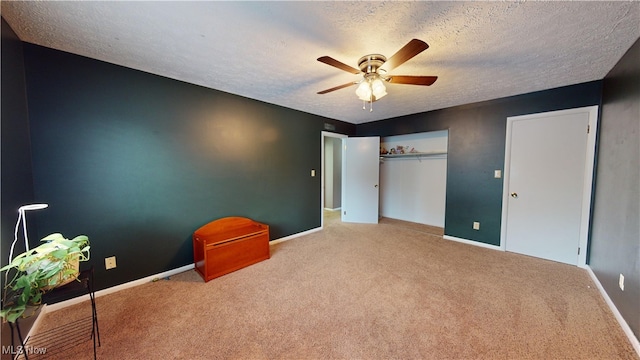 unfurnished bedroom featuring ceiling fan, a textured ceiling, a closet, and carpet floors