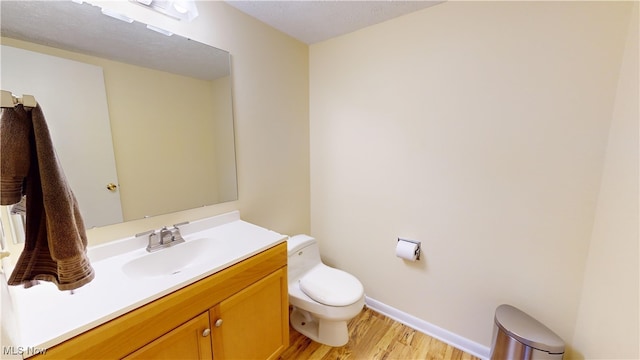 bathroom featuring a textured ceiling, vanity, hardwood / wood-style flooring, and toilet