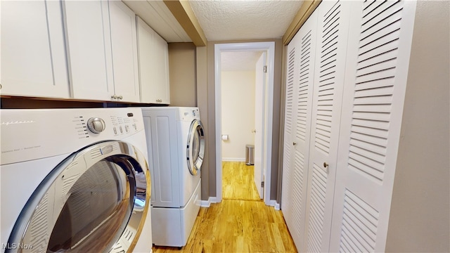 laundry area featuring cabinets, light hardwood / wood-style flooring, a textured ceiling, and washer and dryer