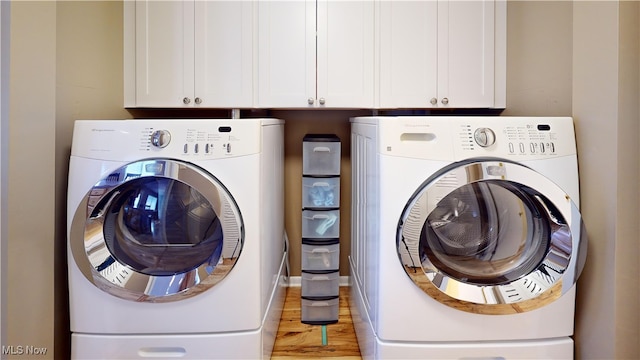 laundry room with cabinets, light hardwood / wood-style floors, and washer and clothes dryer