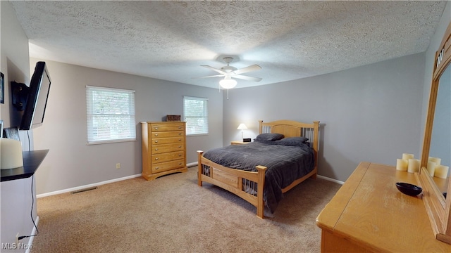 bedroom with ceiling fan, a textured ceiling, and light carpet