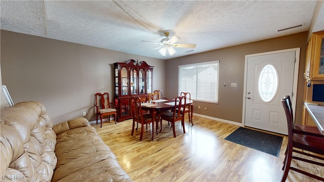 dining space featuring a textured ceiling, light wood-type flooring, and ceiling fan