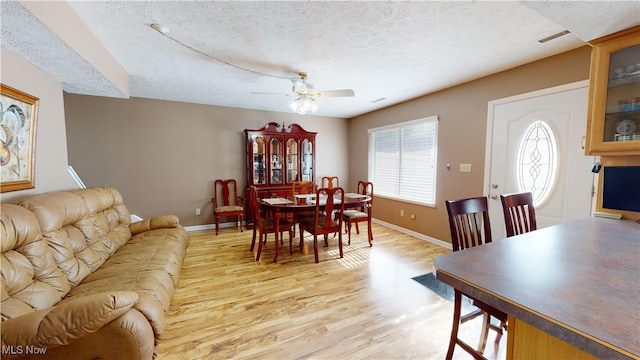 dining room featuring light hardwood / wood-style floors, ceiling fan, and a textured ceiling