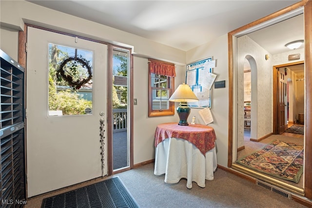 doorway with a healthy amount of sunlight and carpet floors