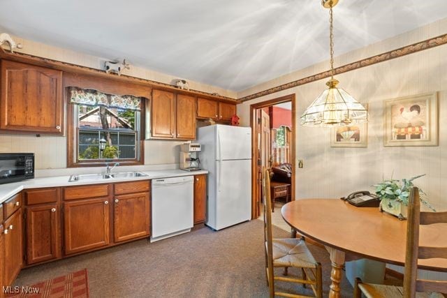 kitchen featuring white appliances, carpet floors, hanging light fixtures, and sink