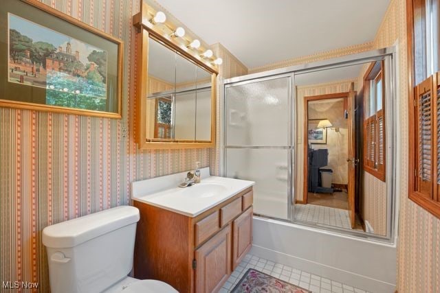 full bathroom featuring tile patterned flooring, vanity, toilet, and bath / shower combo with glass door