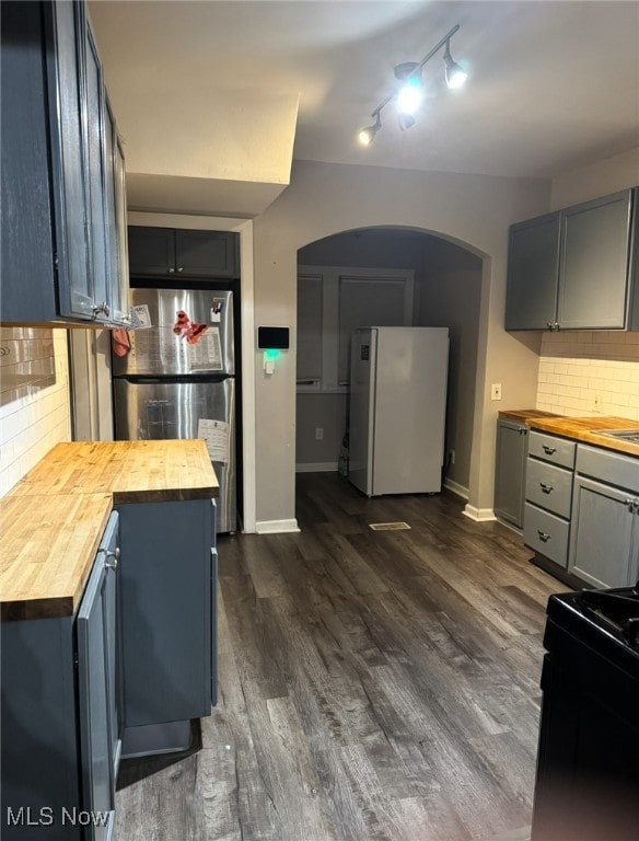 kitchen featuring stainless steel refrigerator, butcher block counters, tasteful backsplash, and white fridge