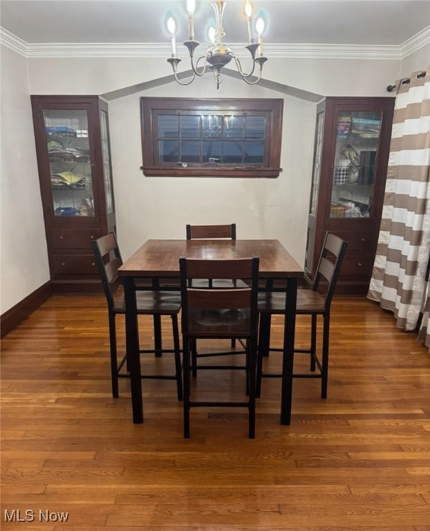 dining room with ornamental molding, dark hardwood / wood-style flooring, and a notable chandelier