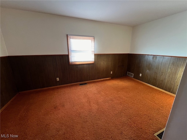 carpeted empty room with wood walls