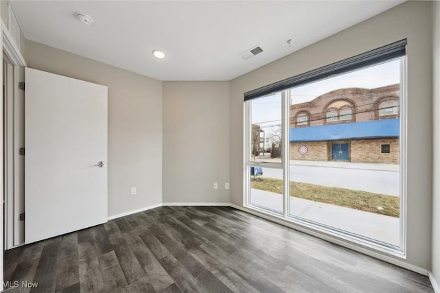 interior space with plenty of natural light, wood finished floors, visible vents, and baseboards