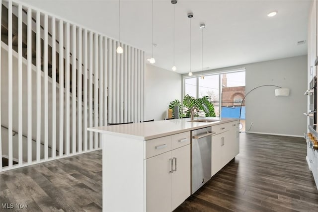 kitchen with a kitchen island with sink, dark wood-style flooring, a sink, white cabinets, and stainless steel dishwasher