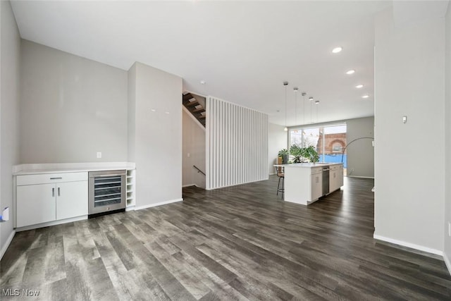 unfurnished living room with baseboards, dark wood-style floors, wine cooler, stairway, and recessed lighting