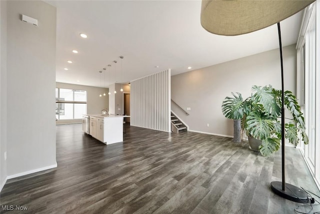 unfurnished living room featuring stairway, baseboards, dark wood-type flooring, and recessed lighting