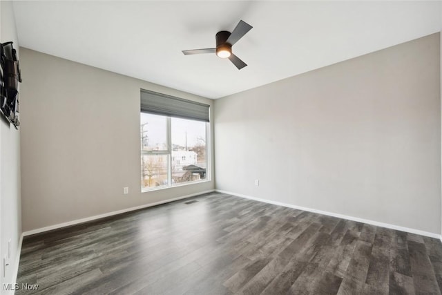 empty room with dark wood-style floors, visible vents, baseboards, and a ceiling fan