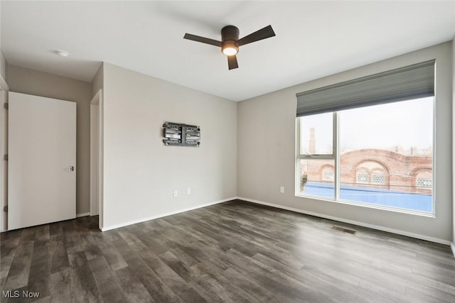 spare room with dark wood finished floors, visible vents, and baseboards