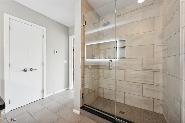 bathroom with a shower stall, baseboards, and tile patterned floors