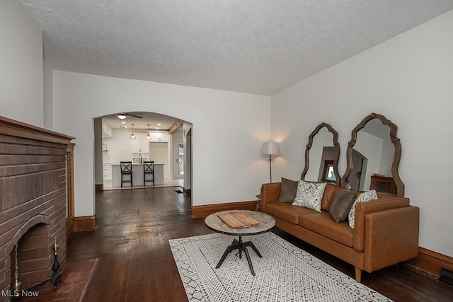 living room featuring dark hardwood / wood-style floors, a textured ceiling, and a fireplace