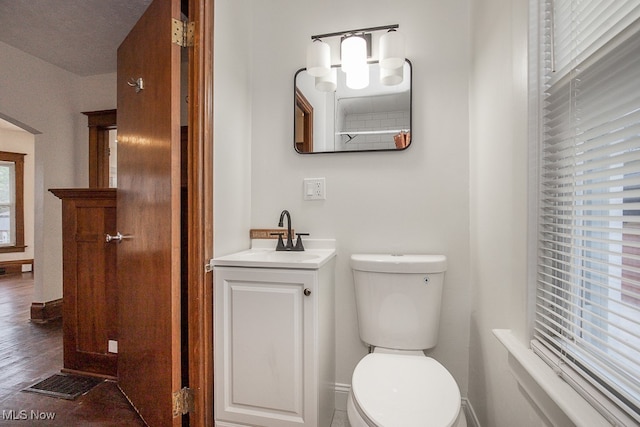 bathroom featuring vanity, toilet, a healthy amount of sunlight, and hardwood / wood-style floors