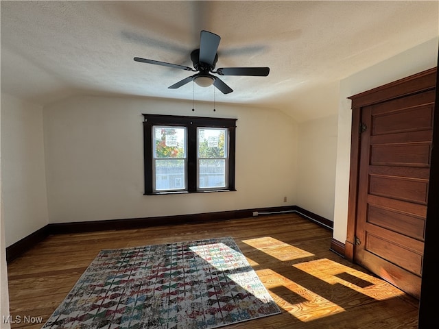 unfurnished room featuring ceiling fan, a textured ceiling, vaulted ceiling, and dark hardwood / wood-style flooring