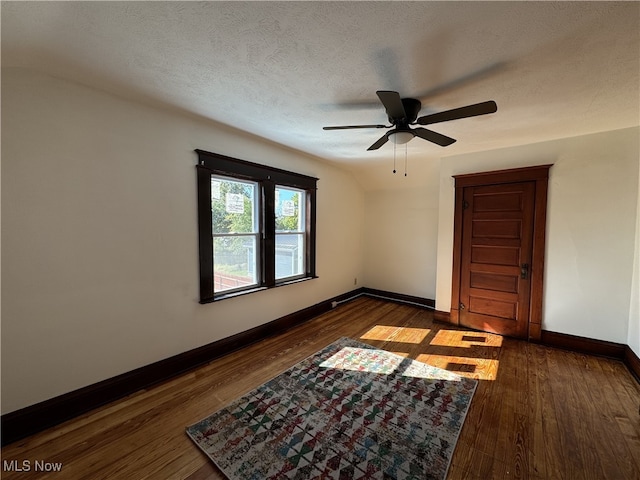 unfurnished room with ceiling fan, a textured ceiling, and dark hardwood / wood-style floors