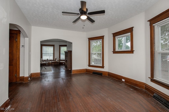 unfurnished room with dark wood-type flooring, a textured ceiling, a healthy amount of sunlight, and ceiling fan