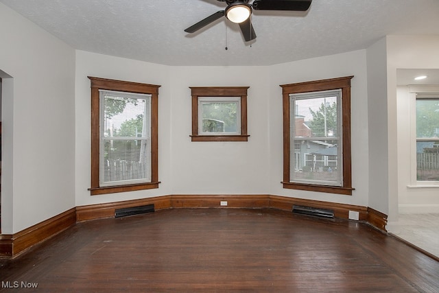 spare room with a textured ceiling, ceiling fan, and dark hardwood / wood-style flooring