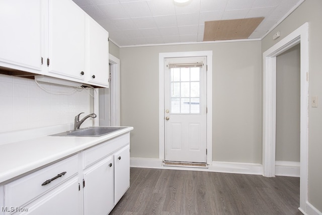 kitchen featuring decorative backsplash, dark wood-type flooring, sink, crown molding, and white cabinets