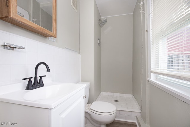 bathroom featuring vanity, walk in shower, toilet, and backsplash