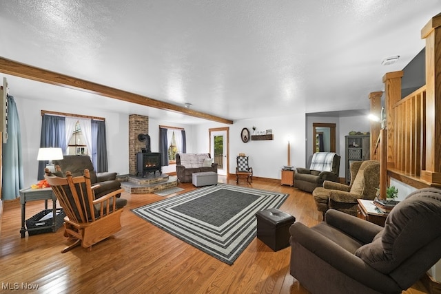 living room featuring a wood stove, a textured ceiling, and light wood-type flooring