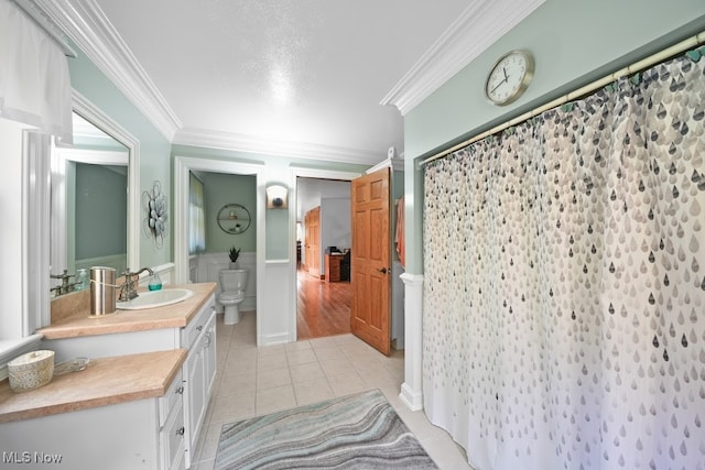 bathroom with toilet, vanity, walk in shower, crown molding, and tile patterned floors