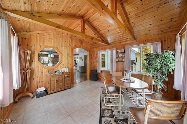 tiled dining space with vaulted ceiling with beams, wooden walls, and wooden ceiling