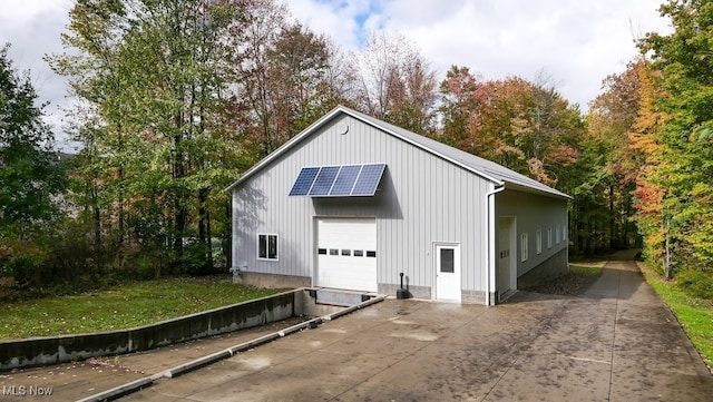 view of outbuilding with a garage and solar panels