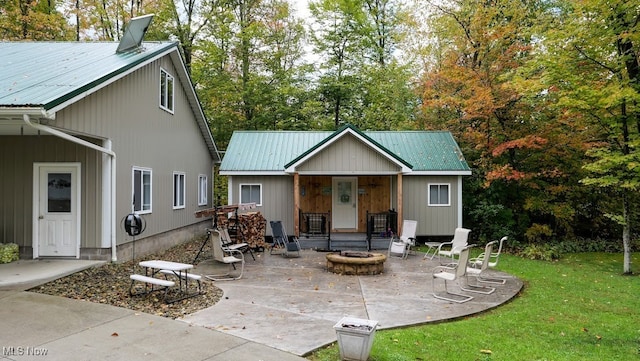 rear view of house featuring a patio, a yard, and a fire pit