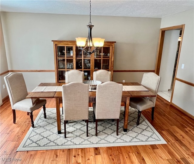 dining room with hardwood / wood-style flooring, a chandelier, and a textured ceiling