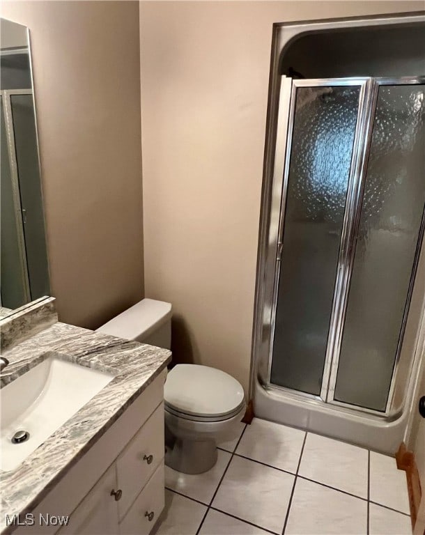 bathroom featuring an enclosed shower, vanity, tile patterned flooring, and toilet