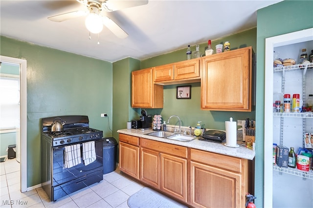 kitchen featuring black gas range, sink, light tile patterned floors, and ceiling fan