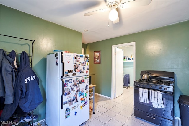 kitchen with light tile patterned floors, ceiling fan, black gas range oven, and white refrigerator