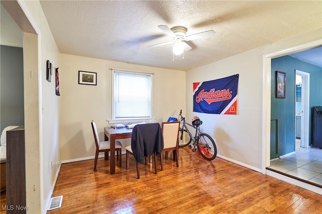 dining room with hardwood / wood-style floors, a textured ceiling, and ceiling fan