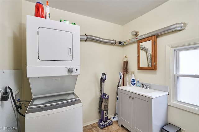 washroom with sink, cabinets, and stacked washing maching and dryer