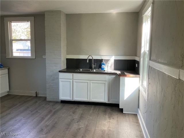 kitchen with sink, white cabinets, and wood-type flooring