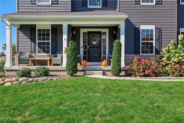 doorway to property featuring covered porch and a lawn