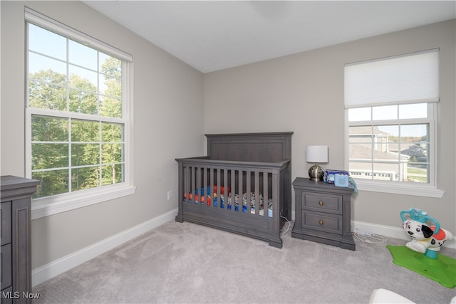 bedroom with a nursery area and light colored carpet