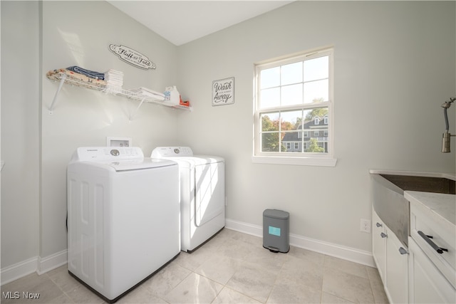 clothes washing area featuring independent washer and dryer, light tile patterned floors, and cabinets